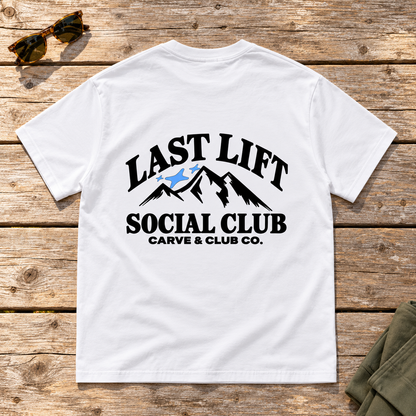 Last Lift Social Club Tee — back view flat lay on wood tabletop