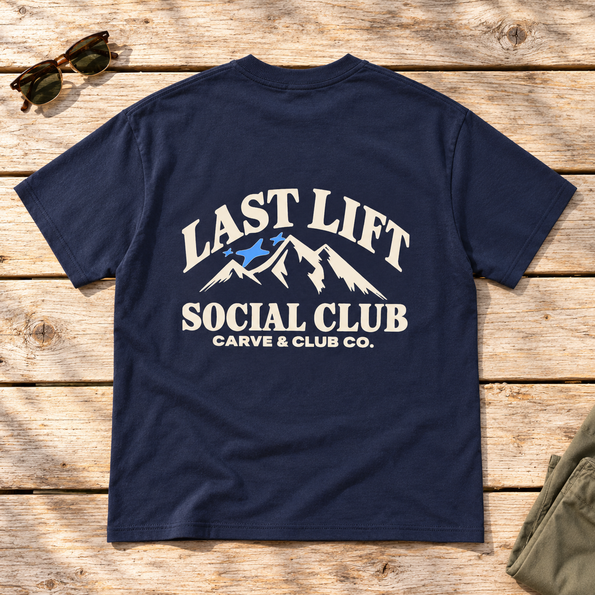 Last Lift Social Club Tee — back view flat lay on wood tabletop