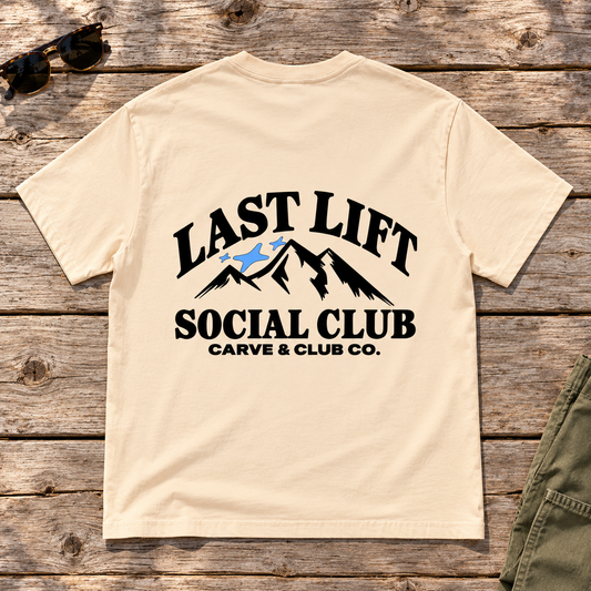Last Lift Social Club Tee — back view flat lay on wood tabletop