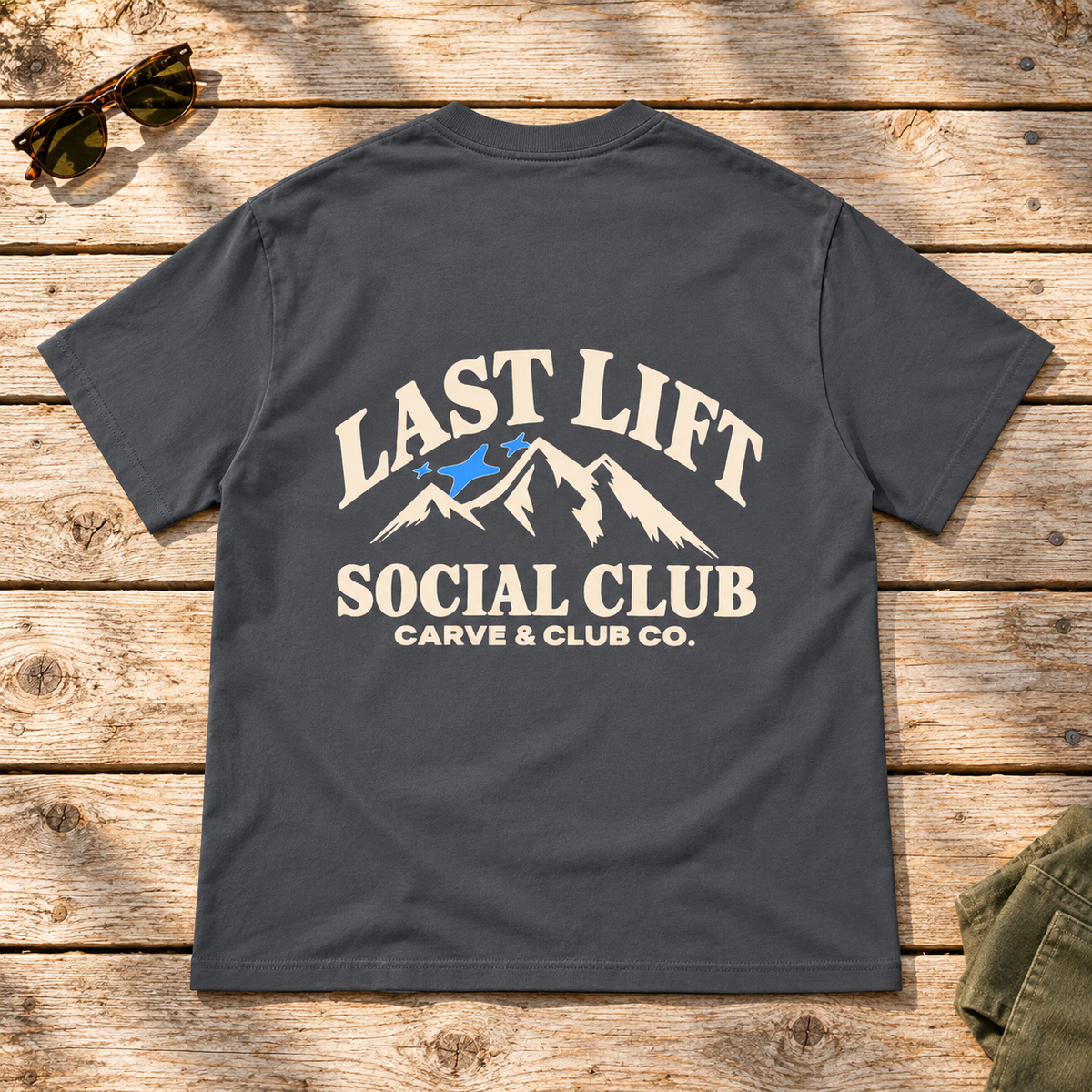 Last Lift Social Club Tee — back view flat lay on wood tabletop